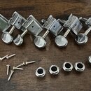 Sada šesti stříbrných kovových ladicích kolínek s kulatými knoflíky. Pod nimi jsou rozložené dvanácti kovové šroubky a šest stříbrných podložek. Všec…