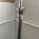 Detail chromovaného kovového stojanu s utahovacím mechanismem. Na prstenci je viditelné logo MAPEX. Povrch vykazuje mírné známky opotřebení a drobné…