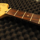 Detail krku a hlavy elektrické kytary s hnědým hmatníkem a světlou dřevěnou hlavou. Na hlavě je vidět nápis "Squier STRATOCASTER". Nástroj má chromov…