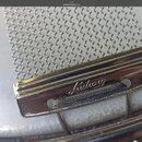 Detailní záběr na kovový mechanismus pružin snare drumu. Na chromovaném držáku je vyryto logo Ludwig. Povrch vykazuje drobné známky opotřebení a zneč…