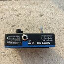 Fotografie zachycuje spodní stranu černého efektpedálu. Na modrém štítku jsou nápisy „USE ONLY 9V DC ADAPTER“, „Designed and developed entirely by EB…