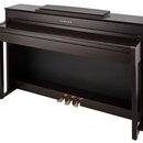 Tmavě hnědé digitální piano v podobě konzole s klaviaturou a třemi mosaznými pedály. Na horní části korpusu je bílý nápis YAMAHA. Nástroj vykazuje hl…