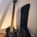 Černá akustická basová kytara s cutawayem a černým obalem. Na hlavě hmatníku je bílý nápis Fender. Nástroj má dřevěný hmatník a světle hnědé proveden…