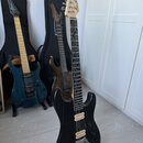Tři elektrické kytary s tvarem typu Superstrat. V popředí je černá kytara s tmavým hmatníkem, bílými snímači a logem Fender na hlavě. Uprostřed stojí…