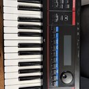 Detailní pohled na ovládací panel a klávesy černého digitálního klavíru. Na červeném nápisu je uvedeno KEYBOARD a v horní části je vidět část nápisu…