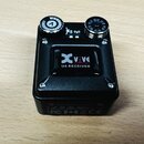 Černý bezdrátový přijímač s kovovým povrchem a dvěma ovládacími knoflíky. Uprostřed je nápis XVive U4 RECEIVER. Na spodní hraně jsou viditelné certif…