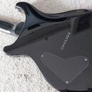 Zadní strana elektrické kytary s černým lesklým povrchem. V dolní části těla je trojúhelníkový kryt elektroniky připevněný třemi šrouby. Pod hmatníke…