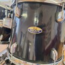 Černý buben s chromovaným kováním. Uprostřed korpusu je oválný štítek s nápisy „Pearl“, „DECADE“ a „MAPLE“. Povrch nástroje vykazuje drobné škrábance…