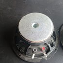 Fotografie zachycuje zadní stranu černého reproduktoru s velkým stříbrným magnetem. Na spodní části jsou vidět dva připojovací terminály, z nichž jed…