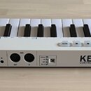 Bílá klaviatura s černými klávesami. Na zadní straně je nápis KEYSTEP CONTROLLER & SEQUENCER a logo Arturia v podobě stylizovaného písmene A v kruhu.…