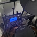 Elektronická bicí souprava značky Carlsbro. Na modrém displeji modulu je vidět nápis USER014 a nad ním texty ELI... (nečitelné) a TEMPLATES. Na padu…