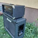 Na fotografii je černý kytarový zesilovač položený na černé kytarové basové bedně. Zesilovač má stříbrné kovové rohy a nápisy Yamaha a YAMAHA TIO. Be…
