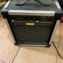 Kytarový kombozesilovač v hliníkovém flightcase s černým povrchem a úchytem. Na horním ovládacím panelu jsou čtyři černé otočné ovladače s popisky GA…