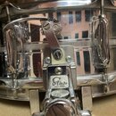 Detailní pohled na chromovaný snare drum s mechanismem napínání. Na kovovém krytu mechanismu je vyryto logo „Star“ a pod ním nápis „PAT. PEND.“. Povr…