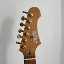 Fotografie zachycuje hlavu elektrické kytary z přírodního dřeva. Na hlavě je umístěno logo "Zet" a nápis "ZET GUITARS". Nástroj má šest zlatých ladíč…