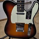 Elektrická kytara typu Telecaster s barevným přechodem korálovo-černé (sunburst) a krémovým pickguardem. Na pickguardu je černý štítek s nápisy „Fend…