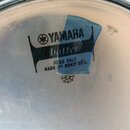 Fotografie zachycuje bílý plastový bubenový kožen s kovovým obručem. Uprostřed je černý nápis YAMAHA s logem, pod kterým je kurzívou napsáno batter a…