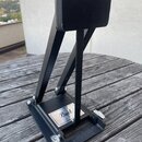 Černý kovový pedál s černou ploščkou. Na spodní základně je viditelné logo Pearl. Předmět vykazuje mírné známky opotřebení povrchu a prach.
