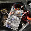 Fotografie zachycuje vnitřek přístroje s elektronickým plošníkem, na kterém jsou připájené kondenzátory, rezistory a tranzistory. Na plošníku jsou vi…