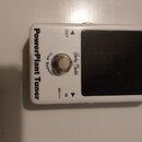 Bílý kytarový pedál s černým displejem. Na levé straně je nápis PowerPlant Tuner, uprostřed logo Harley Benton a text True Bypass. Jsou zde viditelné…