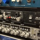 Detailní pohled na rack s audio vybavením. Uprostřed je černý přístroj s nápisy WA-412, TRANSFORMER BALANCED 4 CHANNEL DISCRETE MIC PRE a POWER u vyp…