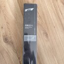 Fotografie znázorňuje úzký černý kartonový obal s produktem uvnitř. Na obalu je bílý nápis CGN 99 H/L a text Condenser Gooseneck Microphone. Ve spodn…