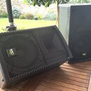 Dva černé reproduktory s kovovými ochrannými mřížkami včerněná perforace. Oba mají na přední straně čtvercový štítek s nápisem KV audio. Povrch skřín…
