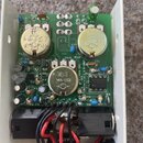Fotografie zachycuje vnitřek efektového pedálu s zelenou základní deskou a zapojenými elektronickými součástkami. Na desce jsou tři kovové potenciome…
