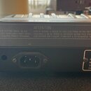 Zadní strana elektronického klávesového nástroje v šedé barvě. Na zadním panelu jsou nápisy CAUTION, ATTENTION a WARNING v angličtině a francouzštině…