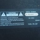 Fotografie zachycuje černý typový štítek s bílým textem a symboly. Jsou na něm uvedeny nápisy CE, logo Fender, MODEL: SP-10™, SERIAL NUMBER AX 065888…