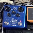Modrý efekt pedál s nápisy Solid Studio, I.R. & Power Amp Simulator a NUX. Zařízení má čtyři černé ovládací knoflíky s popisky Master, Drive a Pres.,…