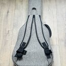 Šedý textilní obal na kytaru s dvěma černými popruhy na zádech. V horní části je bílý stylizovaný znak ve tvaru písmene A. Povrch materiálu je v dobr…