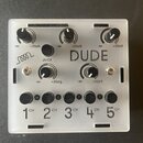 Bílé efektové pedál s nápisem DUDE a ikonou spirály. Zařízení má čtyři otočné ovladače s označením -∞ a +20dB, jedno tlačítko JUICE a pět černých tla…