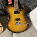 Elektrická kytara s tmelem v přechodu od žluté k tmavě hnědé barvě. Nástroj má dva černá humbuckery, jeden přepínač a dva ovládací knoflíky. Na kytar…
