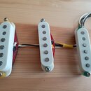 Tři bílé snímače s viditelnými kovovými póly, umístěné na dřevěném podkladu. Snímače jsou propojeny mezi sebou a vedou od nich elektrické vodiče v rů…