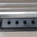 Detailní pohled na zadní panel černého elektronického zařízení. Jsou zde čtyři konektory s nápisy INPUT, OUTPUT (pod nimi označení R a L/MONO) a PHON…