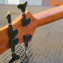 Detail hlavy hnedkového nástroje ze dřeva s čtyřmi černými ladicími mechanismy. Na dřevě nejsou vidět žádné značky, loga ani nápisy. Povrch dřeva je…