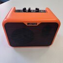 Oranžový kompaktní kytarový zesilovač s černou přední mřížkou. Na horní části jsou tři ovládací knoflíky s popisky VOLUME, TONE a GAIN, vstup INPUT a…