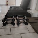 Dvě černé kruhové podložky z materiálu připomínajícího gumu nebo plast. Na bočních stranách obou podložek je viditelný nápis earacoustics. V pozadí j…