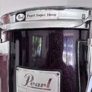 Detail bubnu v tmavě fialové barvě s glitrovým povrchem a chromovanými obručemi. Na horním obruči je nápis „Pearl Pearl Super Hoop“. Na korpusu je ko…