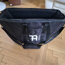 Černá textilní přepravní taška s otevřeným zipem. Na přední straně je bílé logo a nápis MEINL. Taška má dvě krátká ucha a jeden dlouhý ramenní popruh…