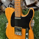 Elektrická kytara typu Telecaster s žlutým dřevěným povrchem těla a černým pickguardem. Hmatník je z jasného dřeva s malými modrými polohovacími znač…