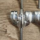 Detailní pohled na chromované ladicí mechaniky z kovu. Na fotografii jsou vidět závitové hroty a upevňovací části mechanismu. Povrch je lesklý, bez v…