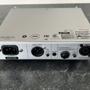 Zadní strana stříbrného elektronického zařízení s kovovým povrchem. Na zadním panelu jsou konektory s popisky AC INPUT, DIRECT OUT, EQ (PRE/POST), AU…