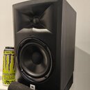 Černý studiový monitor s hornovým výstupem pro vysoké frekvence a kulatým basovým reproduktorem. V dolní části je umístěno bílé logo JBL v černém rám…