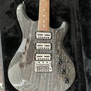 Elektrická kytara s šedým průsvitným lakem, pod kterým je vidět výrazná struktura dřeva. Nástroj má tři humbuckery, jeden tónový potenciometr a jeden…
