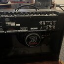Zadní strana černého kytarového komba. Na štítku je uveden výrobce Roland, model KTN-100 2 a sériové číslo GGN681R. Uprostřed je umístěn velký bílý n…