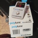 Bílý kytarový tuner v originální krabici. Na přístroji i na obalu jsou nápisy „polytune“ a „tc electronic“, dále je zde text „true bypass“. Displej t…