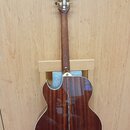 Zadní pohled na akustickou kytaru s hnědým dřevěným povrchem a vyřezem v těle. Na hlavě hmatníku jsou vidět zlaté ladičky a nápis "Ibanez". Nástroj j…