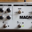 Bílá efektová pedálboard s nápisem MAGNUS a textem by T-REX ENGINEERING - Denmark. Na panelu jsou ovládací prvky pro sekce DELAY, REVERB a tlačítka T…